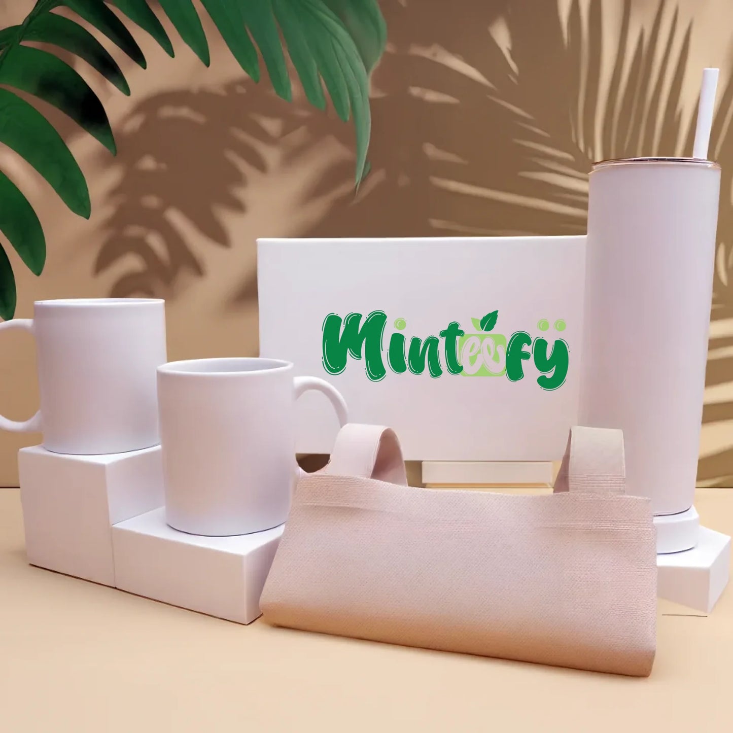 Minteefy branded drinkware, tote, and box set in green and white on a beige tropical background.