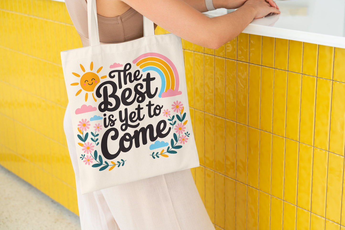 Canvas tote bag with colorful floral and rainbow design and the quote 'The Best is Yet to Come'.