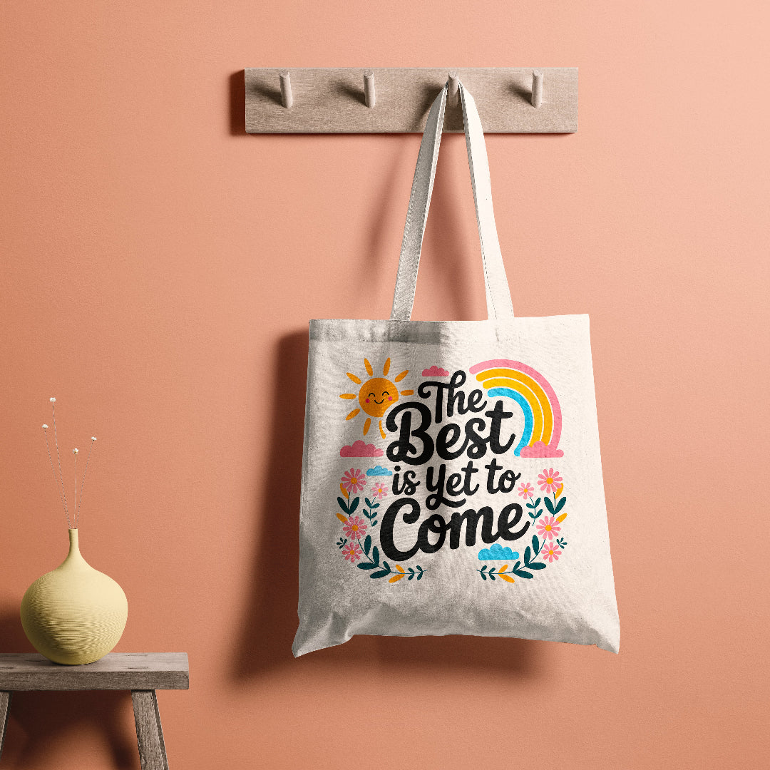 Canvas tote bag with colorful floral and rainbow design and the quote 'The Best is Yet to Come'.