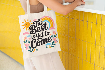 Canvas tote bag with colorful floral and rainbow design and the quote 'The Best is Yet to Come'.