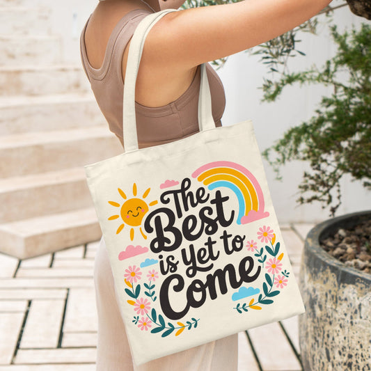 Canvas tote bag with colorful floral and rainbow design and the quote 'The Best is Yet to Come'.